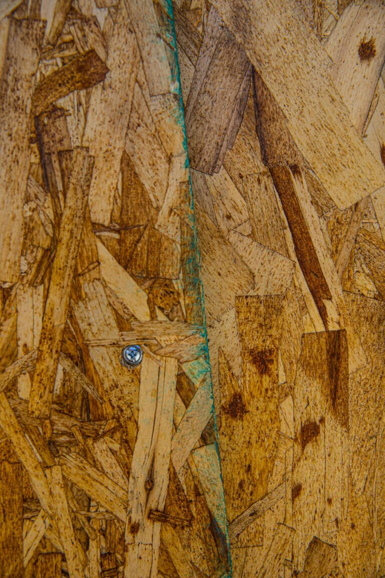 Textured close-up of a rough wooden particle board with visible screw detail.